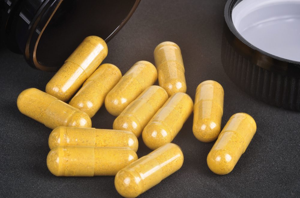 Closeup of a yellow pills coming out of a medicine bottle