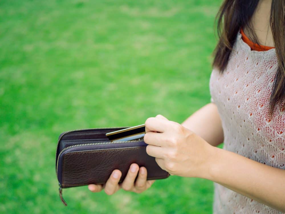 Closeup woman hand putting credit card into leather wallet . Business and financial, money saving concept.