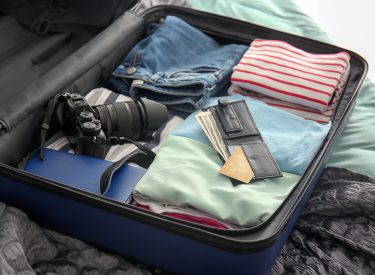 Open suitcase with packed things on bed